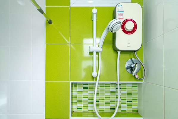 A bathroom with a shower unit, a handheld showerhead, and a wall-mounted faucet.