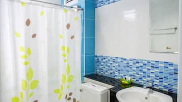 A bathroom with a toilet, a sink, and a shower curtain with leaf patterns.