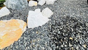 Un jardín con un farol de piedra, rocas y plantas de bambú.