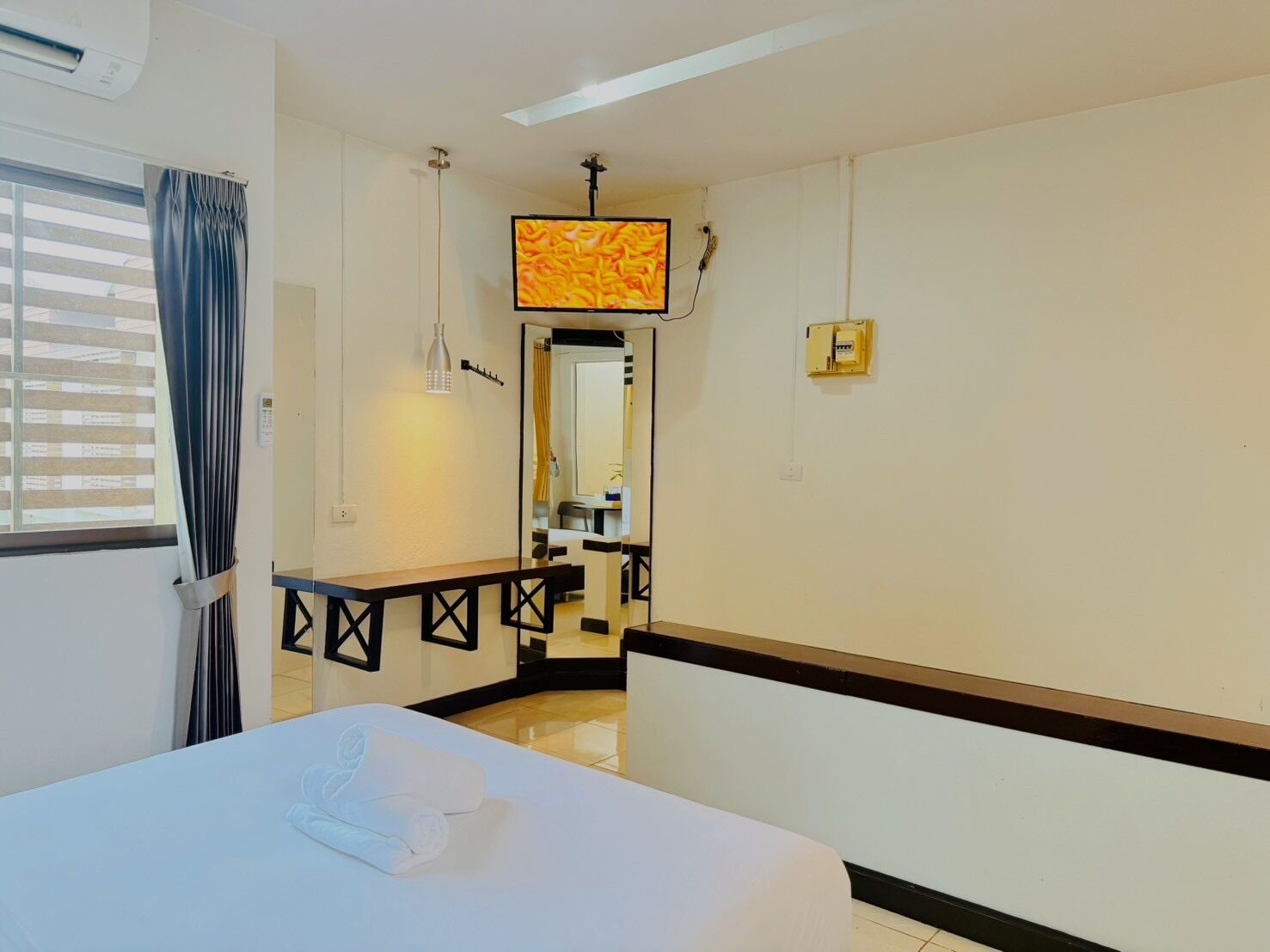 A hotel room with a bed, a desk, a mirror, and a view of the bathroom.
