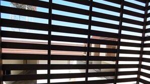 Una habitación con vistas a través de una ventana con persianas horizontales.