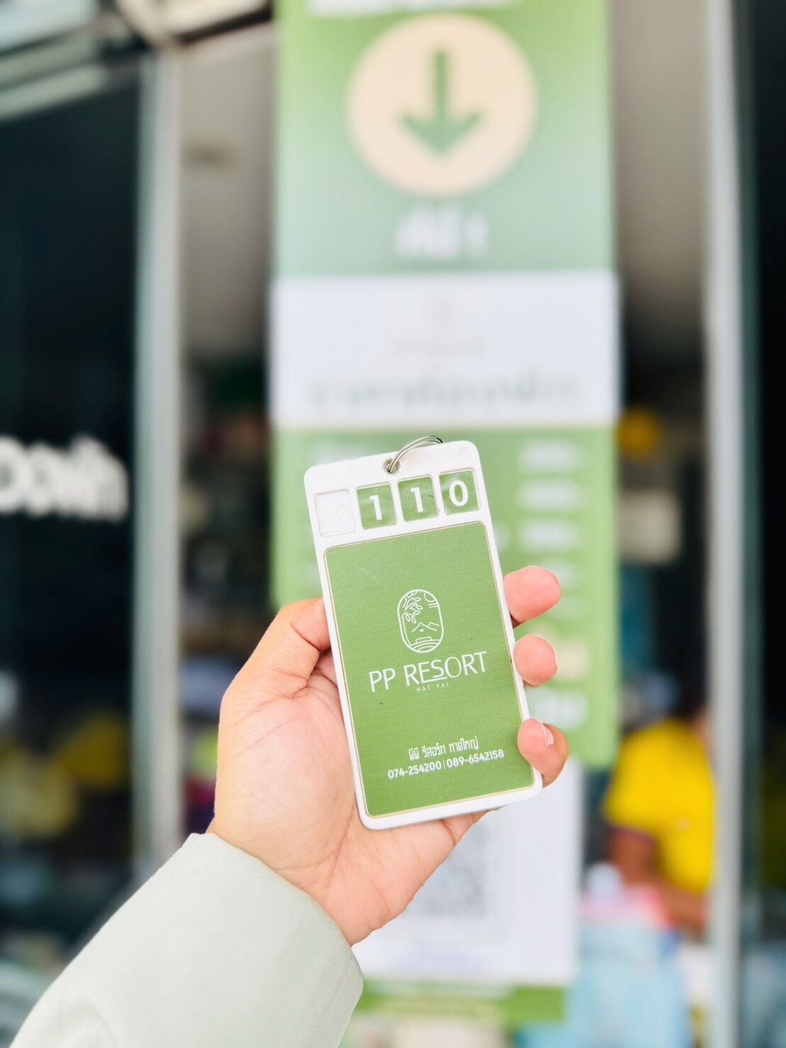 A hand holding a keycard with the text "PP RESORT" and a phone number.
