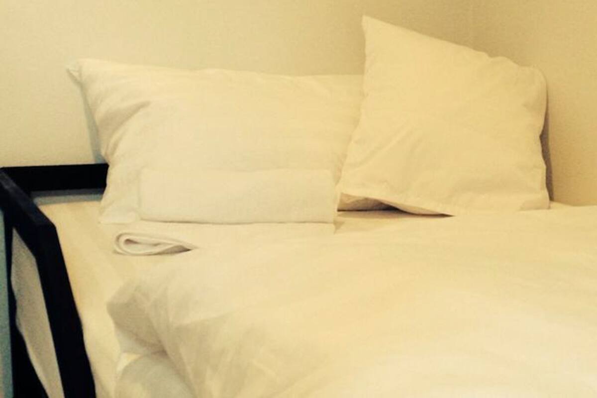 A bed with white bedding and a white pillow.