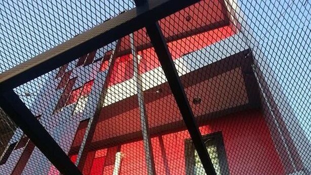 Um edifício moderno com fachada vermelha e branca, estrutura de tela metálica e um lustre pendente.