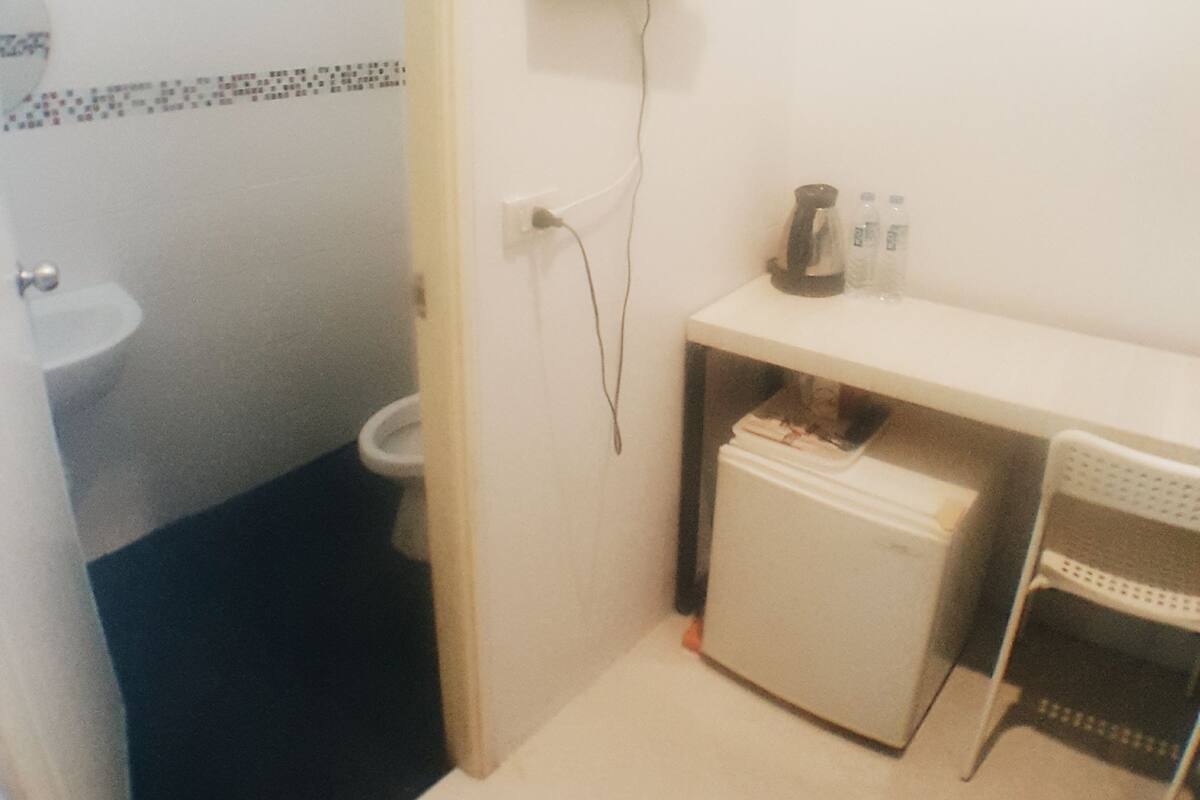 A small bathroom with a toilet, sink, and a television mounted on the wall.