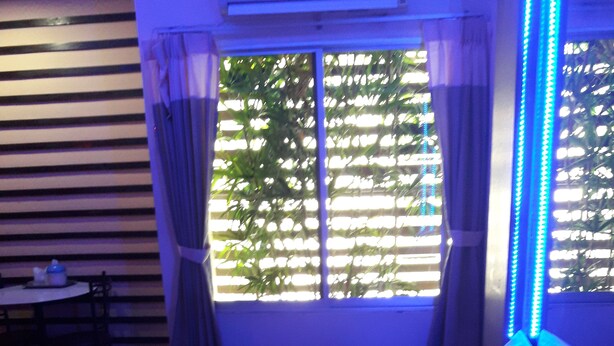 Una habitación con cama, ventana con persianas y una mesa con sillas.