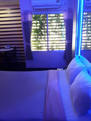 A room with a bed, a window with blinds, and a table with chairs. - PB Resort Hat Yai (Hat Yai)