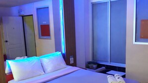 Una habitación de hotel con una cama, una mesita de noche, una ventana y una puerta.