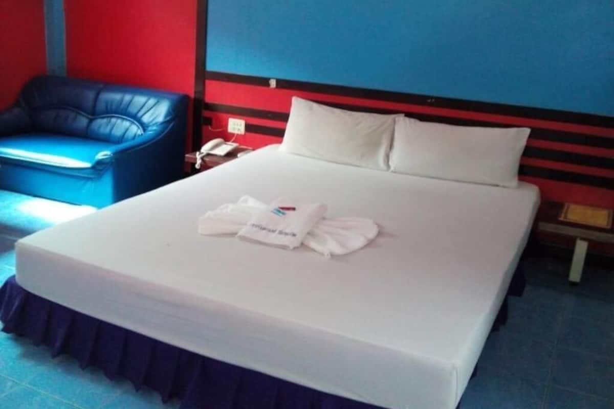 Una habitación de hotel con una cama, una silla azul y una pared roja y azul.