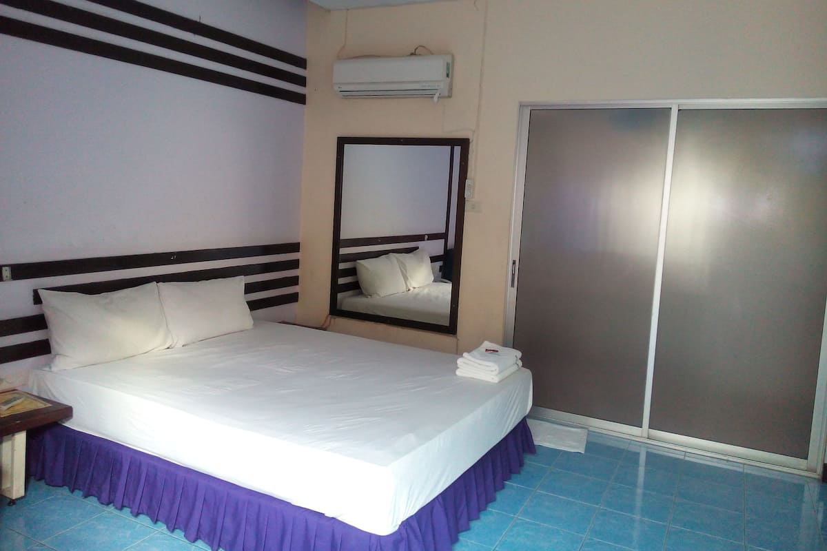 Habitación de hotel con cama, espejo, armario y aire acondicionado.