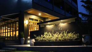 A modern building with a well-lit entrance, large windows, and a sign with Thai script.