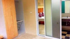 A room with a sliding door leading to a bathroom, a wooden door, and a checkered floor. - Win Resort Hat Yai (Hat Yai)