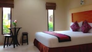 A hotel room with a bed, a small table with a chair, and a window with a view of greenery. - Win Resort Hat Yai (Hat Yai)