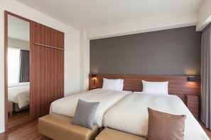 A hotel room with a large bed, a wooden wardrobe, and a mirror.