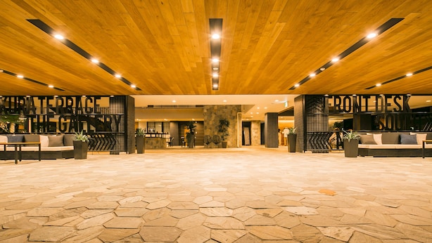 A spacious lobby with a wooden ceiling, hexagonal stone flooring, and seating areas labeled "WATER TOWER LOUNGE" and "FRONT DESK." - Sakura Terrace The Gallery (Kyoto)