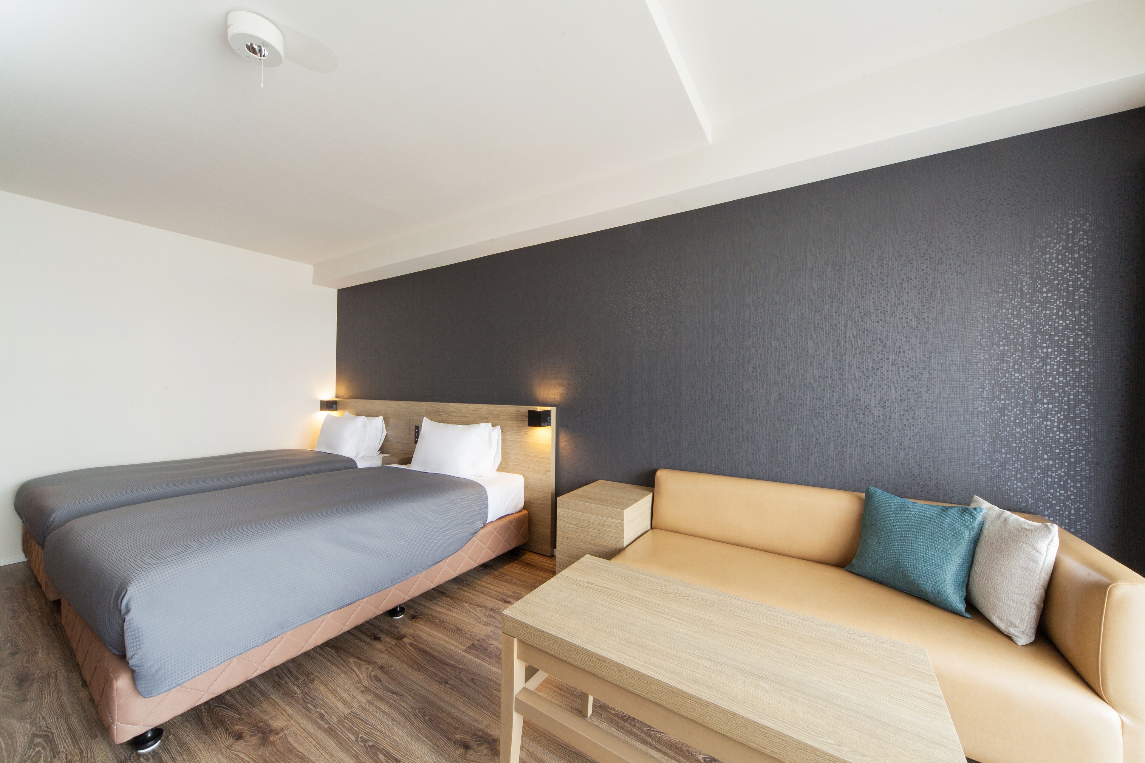 Een moderne hotelkamer met een bed, een bank, een klein tafeltje en een wandlamp.