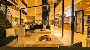A modern hotel atrium with a central fire feature, outdoor seating, and a staircase leading to upper floors. - Sakura Terrace The Gallery (Kyoto)