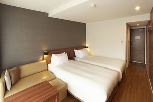 A hotel room with a bed, a sofa, a small table, and a wooden floor.