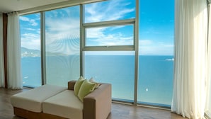 A spacious room with a large window offering a view of the sea and distant land. - Fusion Suites Da Nang (Da Nang Municipality)