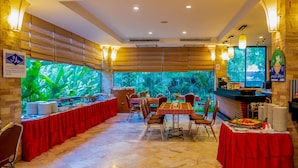 A restaurant with a long table set for a meal, surrounded by chairs, and a counter with a menu. - Hatyai Paradise Hotel (Hat Yai)