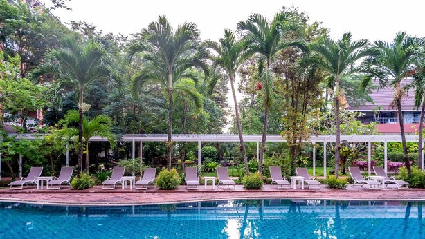 A swimming pool with lounge chairs and palm trees. - Hatyai Paradise Hotel (Hat Yai)
