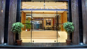 A hotel entrance with a glass door, two potted plants, and a staircase leading to the lobby. - Hotel Chams (Tetouan)
