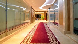 A modern hotel corridor with glass walls, a red carpet, and a curved ceiling. - Hotel Chams (Tetouan)