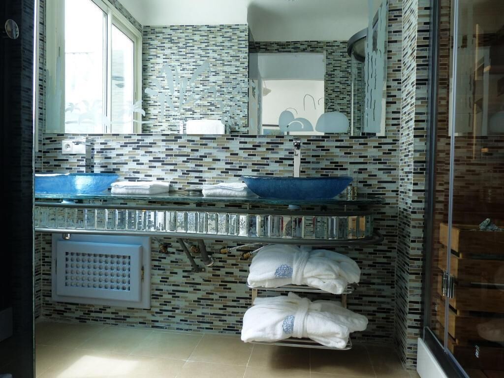 A bathroom with a blue sink, white towels, and a tiled backsplash.