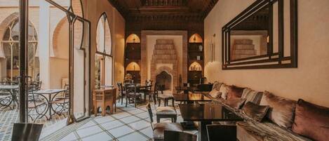 An interior with a dining area, sofas, and a patterned floor.