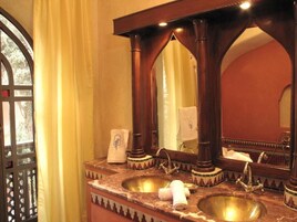 A bathroom with two sinks, a large mirror, and a window with curtains.