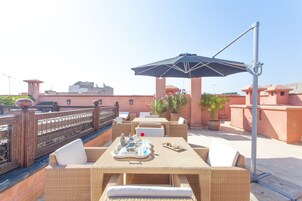 Un patio al aire libre con mobiliario de mimbre, una mesa con bandeja y un paraguas grande.