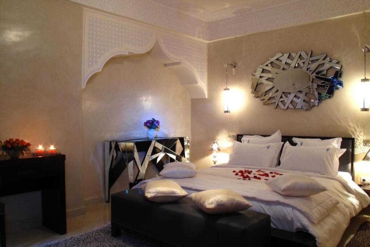 A bedroom with a bed, bedside tables, a decorative wall piece, and a nightstand with a vase.
