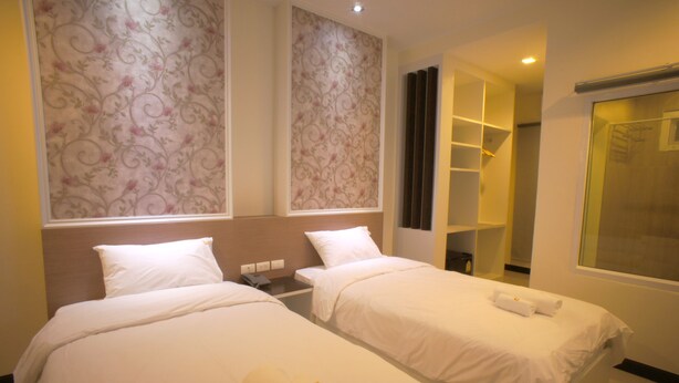 Quarto de hotel com duas camas, um guarda-roupa, banheiro e chuveiro.