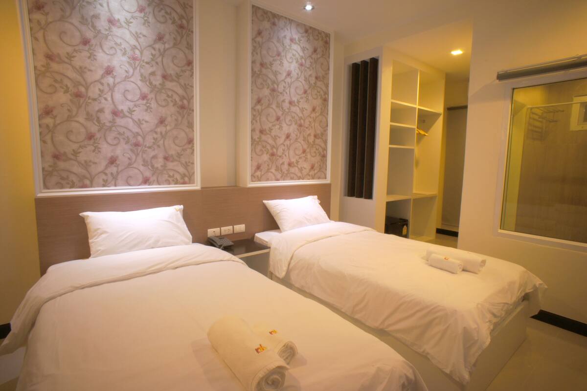 Une chambre d’hôtel avec deux lits, une armoire, une salle de bain et un espace douche.