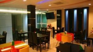 Um restaurante moderno com mesas, cadeiras, uma televisão de tela plana e uma divisória de vidro.