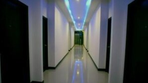 Corredor comprido e estreito, com piso espelhado e paredes brancas.