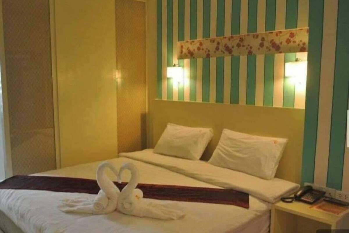 Une chambre d’hôtel avec un lit, des oreillers, une table de chevet avec un téléphone et un mur recouvert d’un papier peint à rayures.