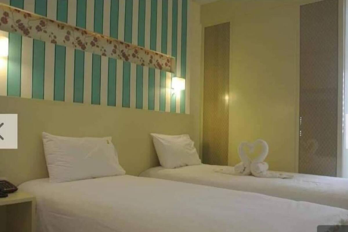 Une chambre d’hôtel avec deux lits, un mur à rayures et une décoration en forme de cœur réalisée avec des serviettes.