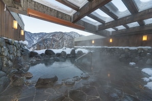 A hot spring area with stone flooring, wooden walls, and a view of snow-covered mountains. - Hotel Morinokaze Tateyama (Toyama)