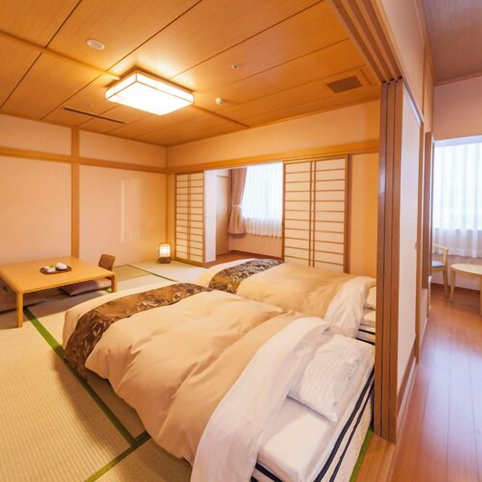 Een traditionele Japanse kamer met tatami vloeren, een laag houten bed, een klein tafeltje met een kussen en verschuifbare shoji deuren.