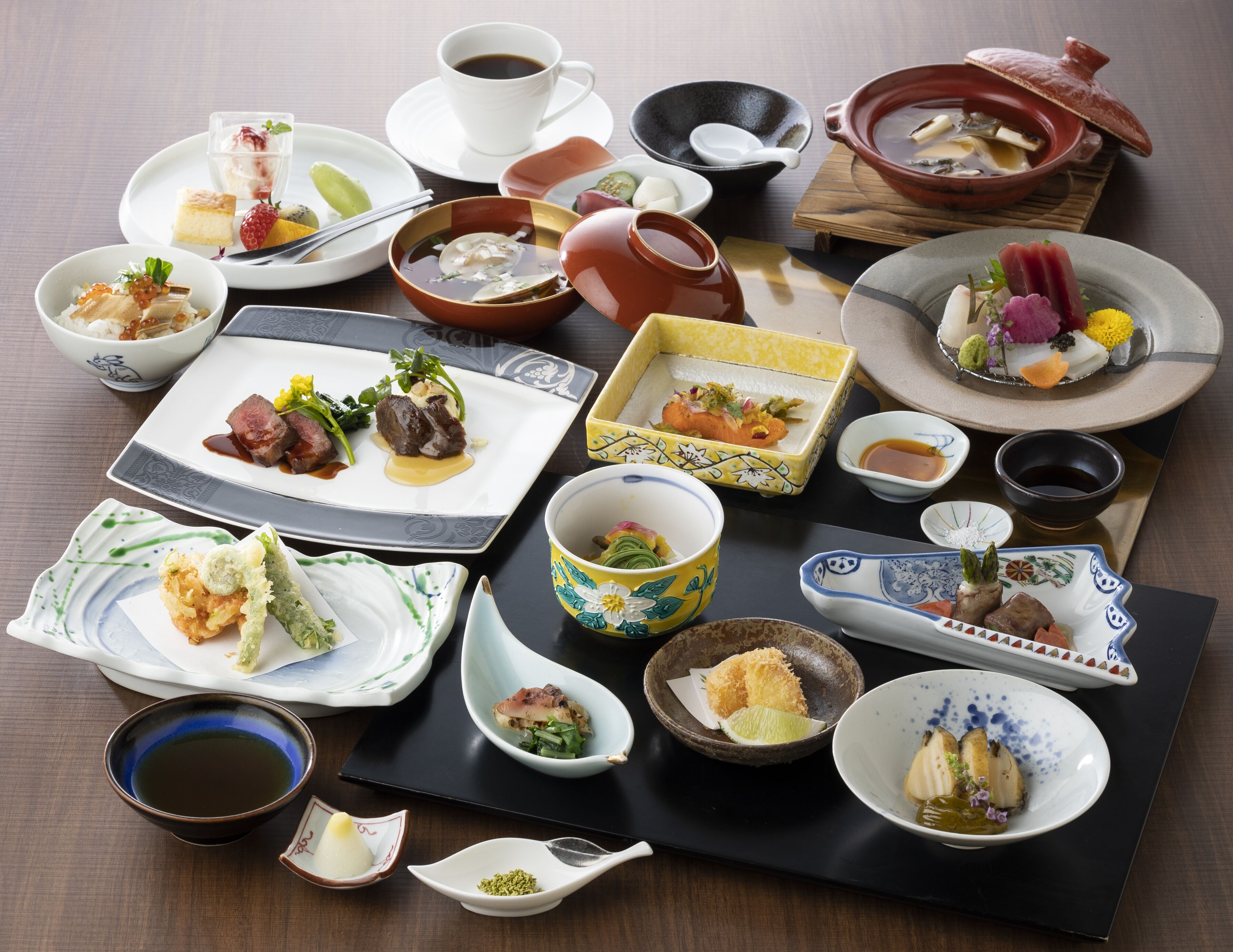 Variedad de platos japoneses dispuestos sobre una mesa, incluyendo sushi, sashimi y otras exquisiteces, acompañados de pequeños cuencos de salsa de soja y té.