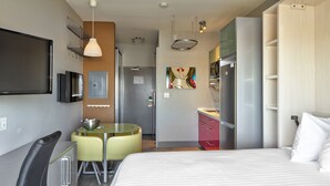 Una habitación de hotel con cama, escritorio, silla, televisión, microondas y refrigerador.