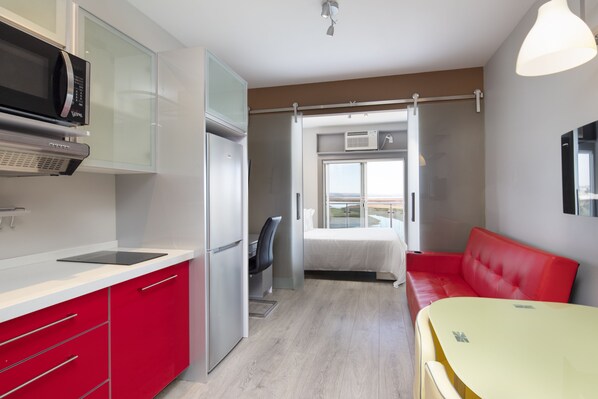 A compact kitchen with modern appliances, a dining area with a yellow table, and a red sofa. - Micro Boutique Living Wolfville (Wolfville)