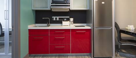 A modern kitchen with a stainless steel refrigerator, a microwave, and a coffee maker on the counter.