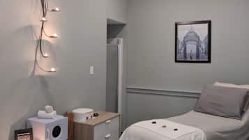 Cozy retreat with a neatly made bed, bedside table, and wall-mounted light fixture.