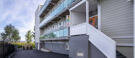 Un immeuble à plusieurs étages doté d’un espace extérieur couvert, d’un escalier et d’une enseigne indiquant une petite entrée.