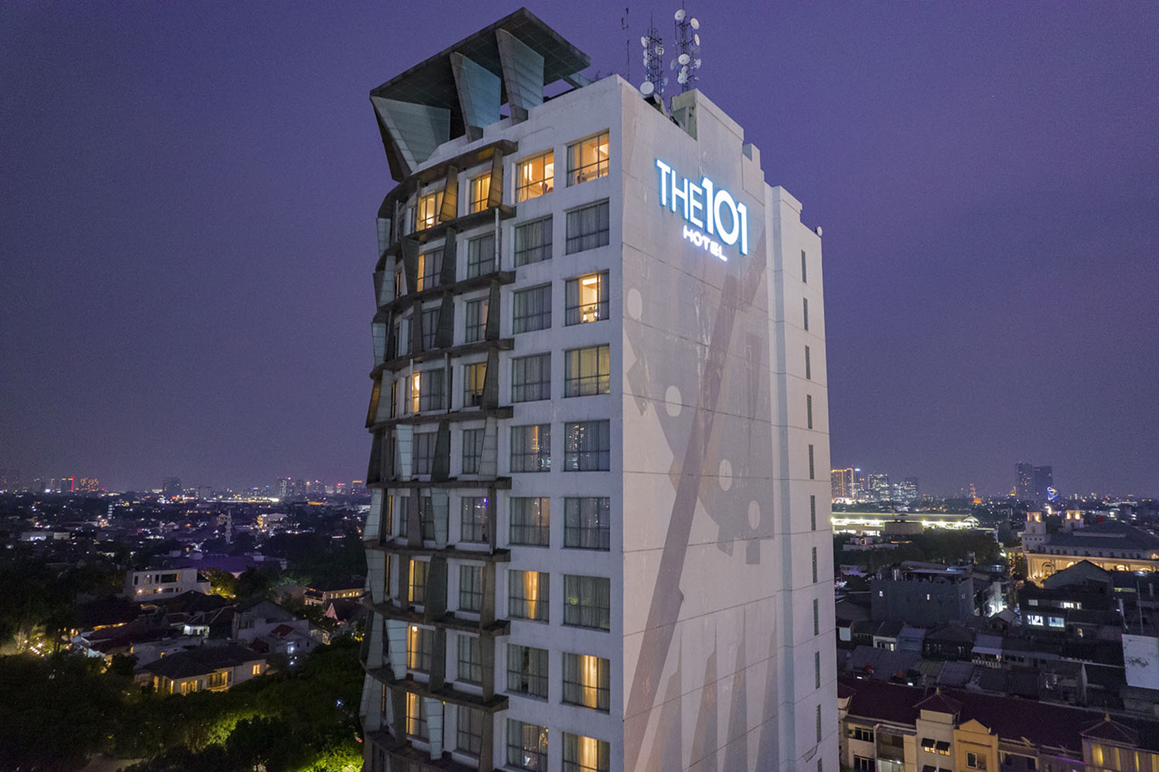 A high-rise hotel with multiple floors, a prominent sign, and a cityscape in the background.