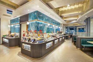 Eine moderne Frühstücksbar mit blauer Mosaikwand, einem Buffet mit verschiedenen Speisen und Sitzbereichen.