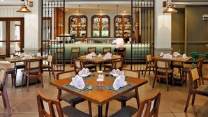Un restaurant avec plusieurs tables dressées pour le service, un coin bar et une vue sur le bar.