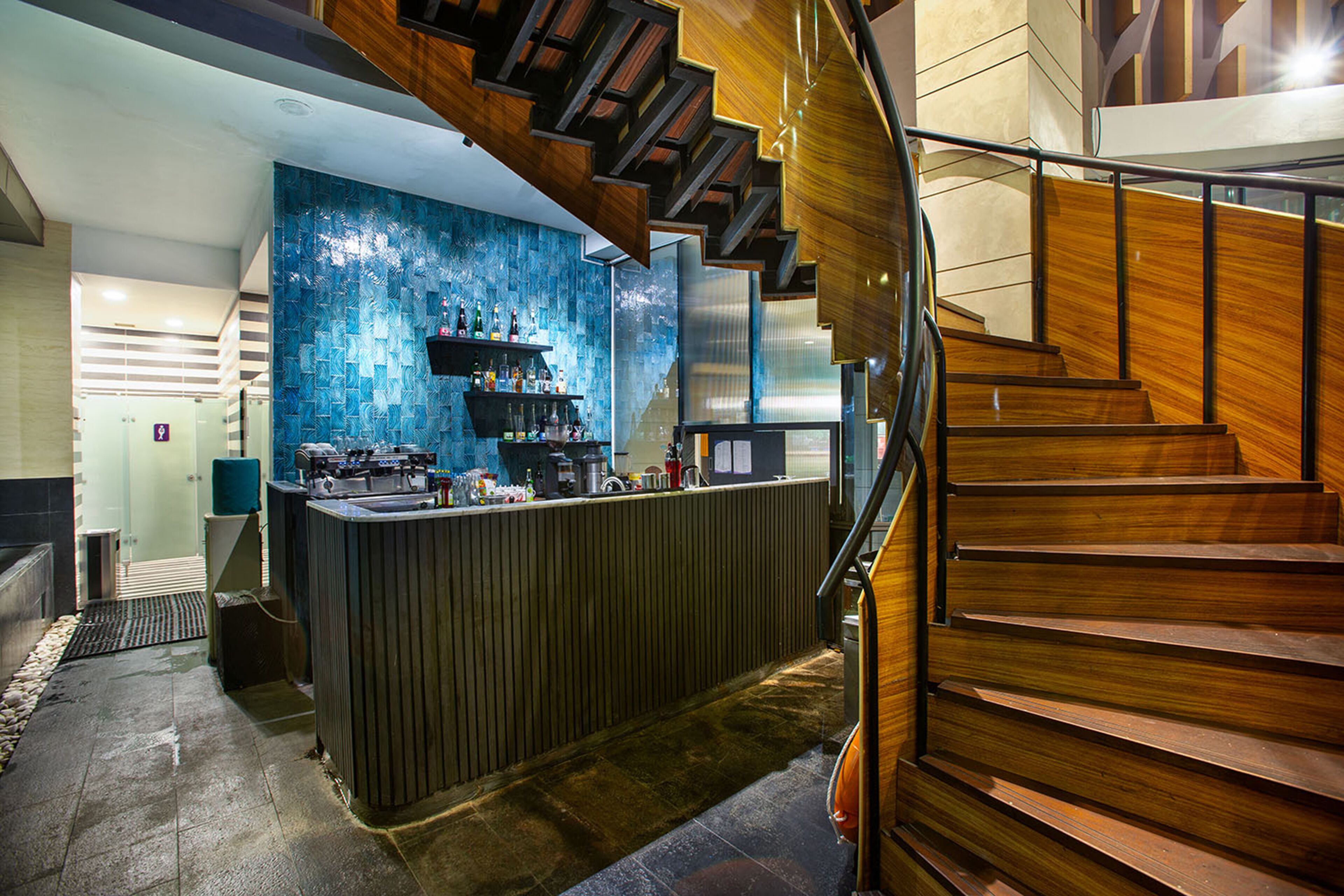 Eine moderne Bar mit einer Holztreppe und einer blauen, strukturierten Wand.